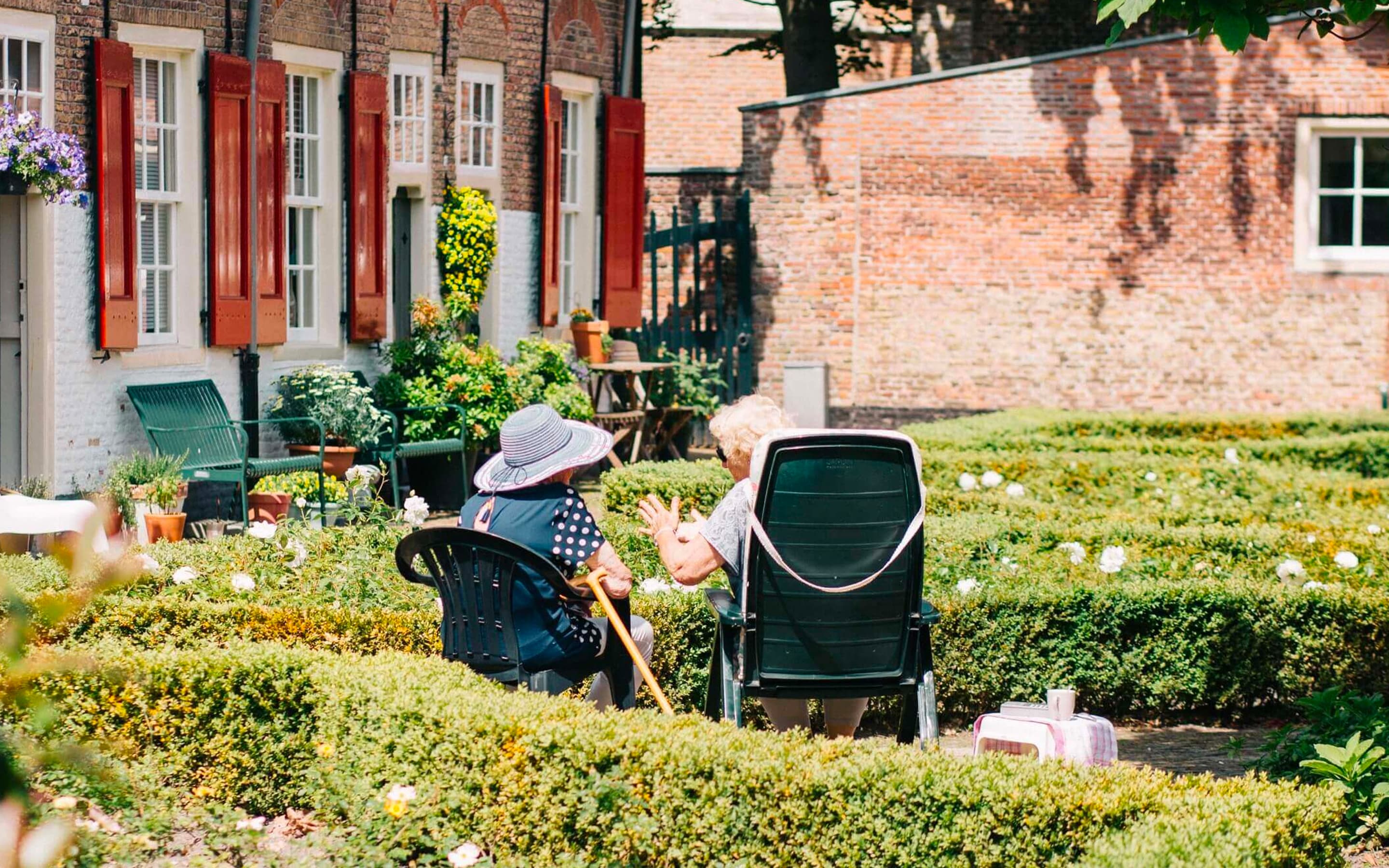 Abbildung von zwei älteren Damen die auf einem Gartenstuhl sitzen