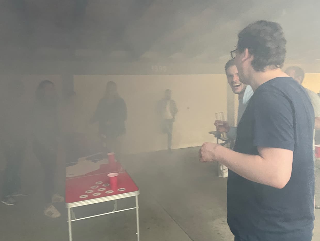 vernebelte Szenerie einer Zusammenkunft bei welcher Bier Pong gespielt wird