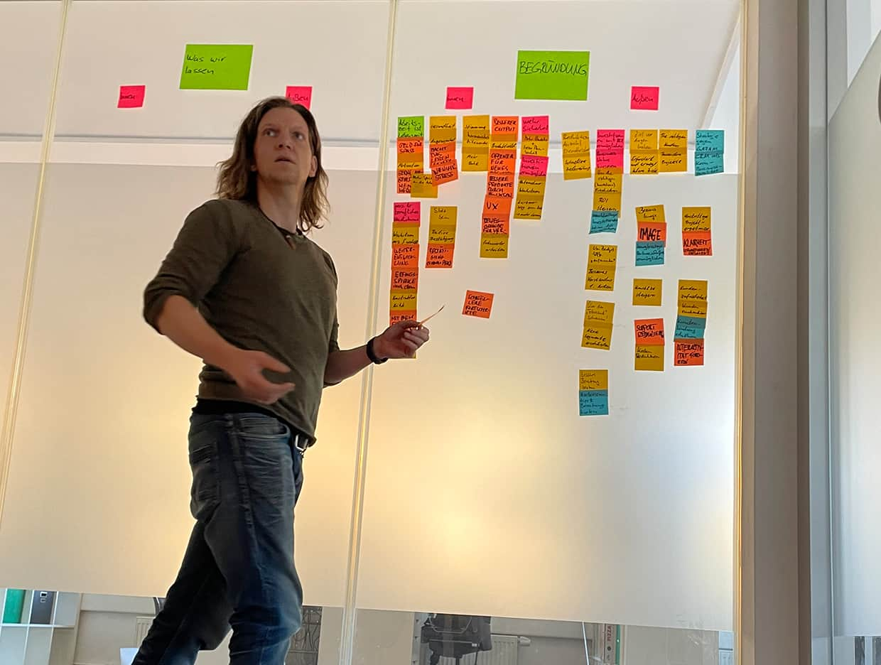 Oliver Schwarzweller steht vor einer Wand mit ganz vielen Post its