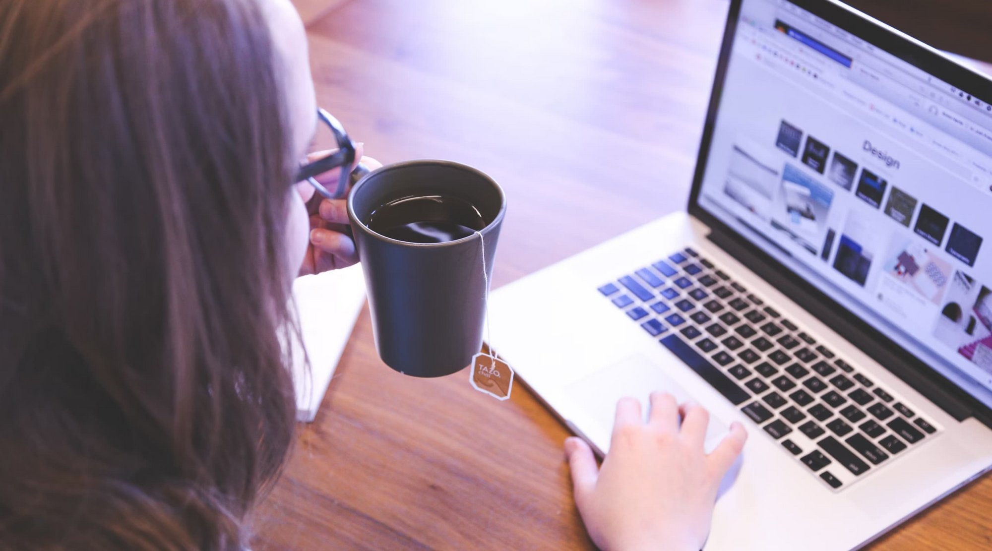 Bild Frau sitzt mit Kaffee an einem Laptop