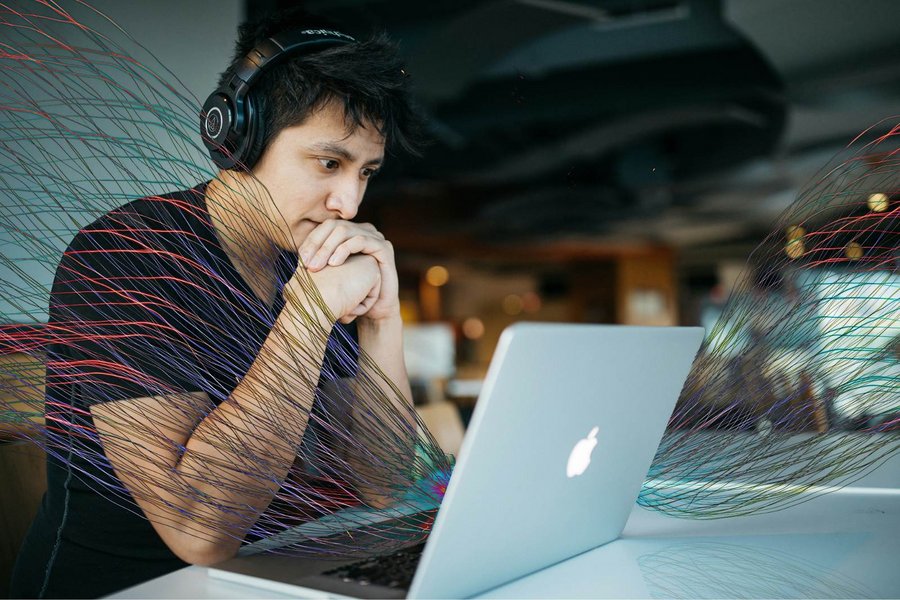 Mann mit Kopfhörer schaut auf einen Laptopn