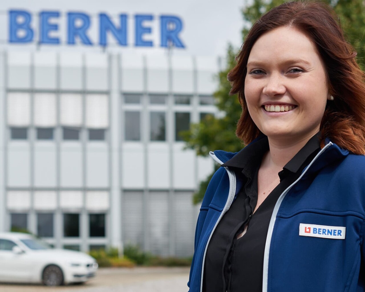 Bild mit einer Frau, welche im Vordergrund eines Gebäude und dem Berner Logo steht