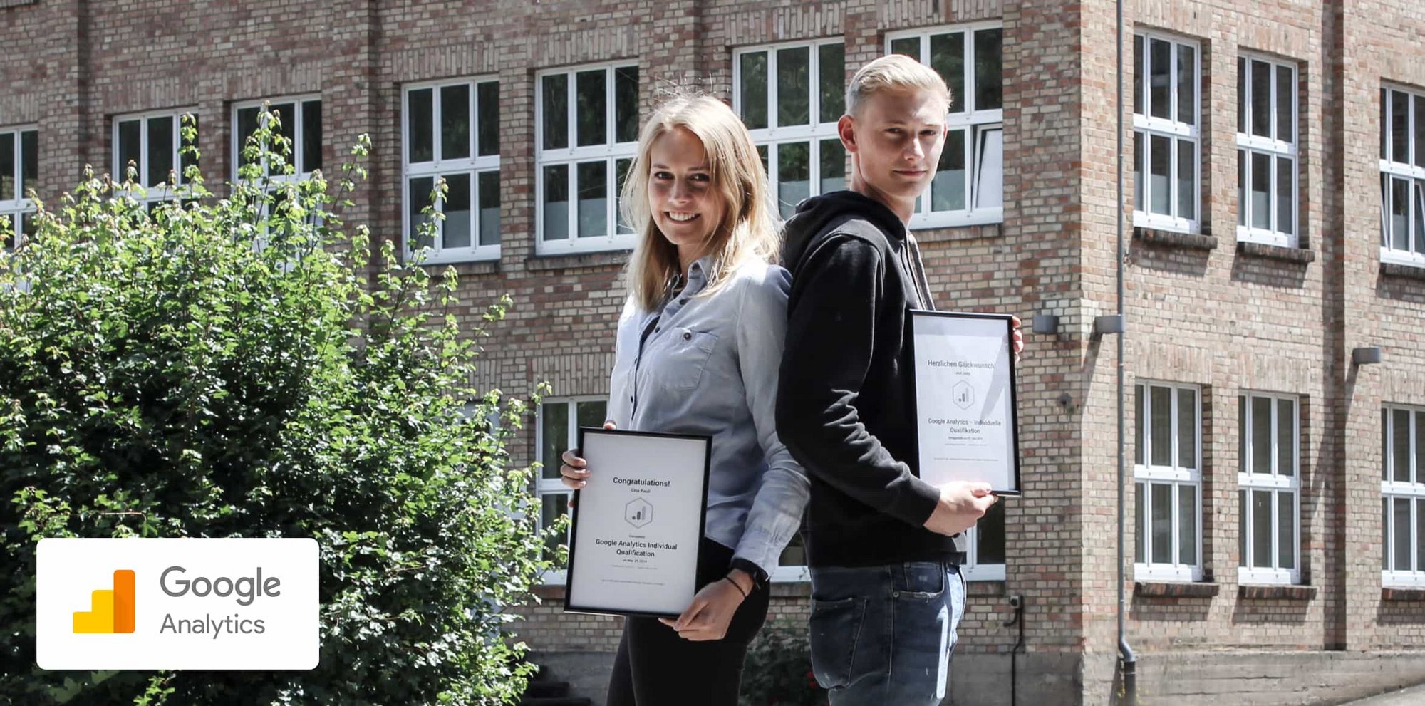 Google Analytics zertifizierung erfolgreich abgeschlossen Lina und Leon stehen draußen vor dem Reizwerk-Büro und halten ihre Zertifikate in die Kamera